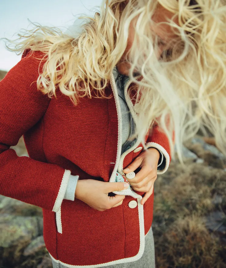 Detailansicht rote Sarner Strickjacke mit weißen Knöpfen und cremefarbener Einfassung